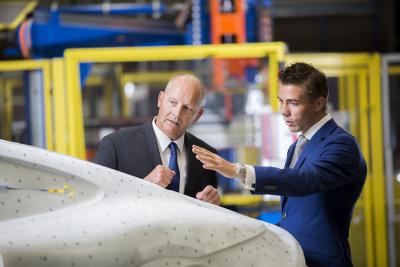 Two business colleagues looking at a car panel, deep in discussion