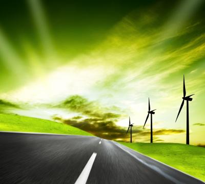 Futuristic view showing a country road with wind turbines on the right side and a green sky