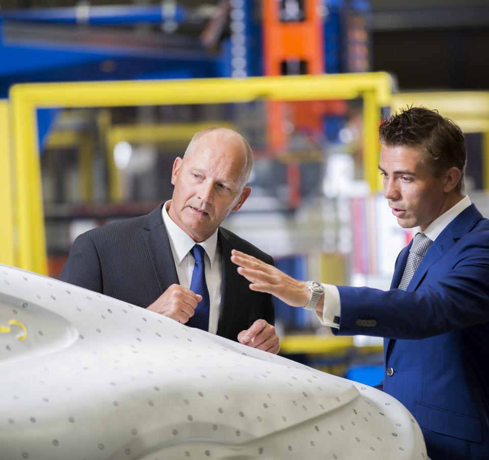 Two business colleagues looking at a car panel, deep in discussion